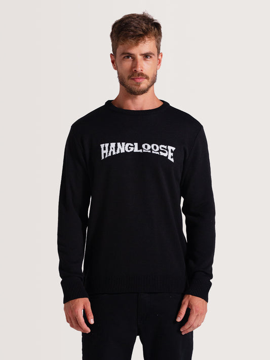 Homem vestindo a blusa tricot preta com palavra  "Hang Loose" branca no peito, mangas longas e gola redonda, sobre fundo claro.