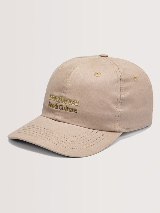 Boné aba curva bege com bordado "Hang Loose Beach Culture" em tom dourado e costuras visíveis. Fundo claro destaca o acessório casual.