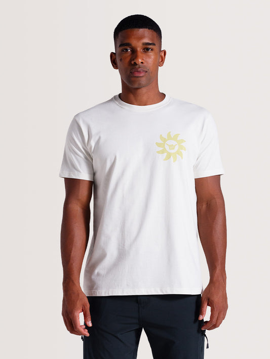 Homem vestindo camiseta off white estampada com design frontal vibrante do sol, posando contra um fundo neutro claro.