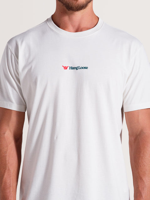 Homem vestindo a camiseta off white manga curta com gola redonda, estampa minimalista "Hang Loose" no peito.