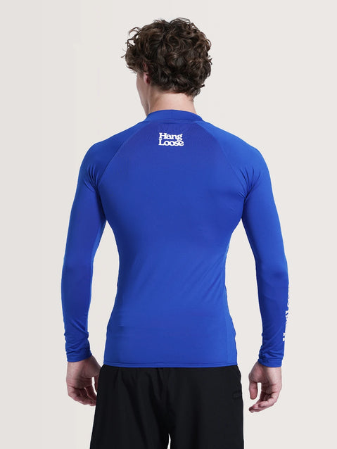 Parte de trás da camiseta surf manga longa azul. Na parte superior há "Hang Loose" escrito em branco.