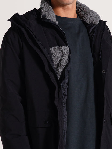 Homem vestindo uma jaqueta pesada preta 3 em 1 com forro interno de lã cinza visível, proporcionando conforto térmico e estilo funcional.