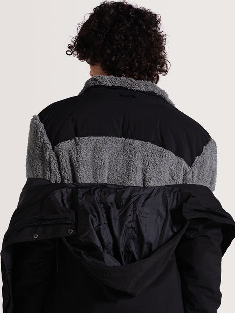 Homem de costas vestindo uma jaqueta pesada preta 3 em 1, com forro de lã cinza visível e parte externa preta