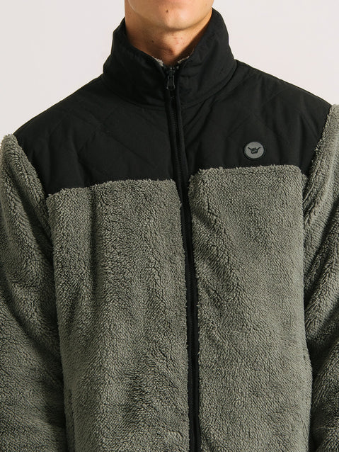 Close da jaqueta pesada preta 3 em 1, destacando a textura de lã cinza, gola alta e parte superior preta com detalhe de logo discreto no peito.