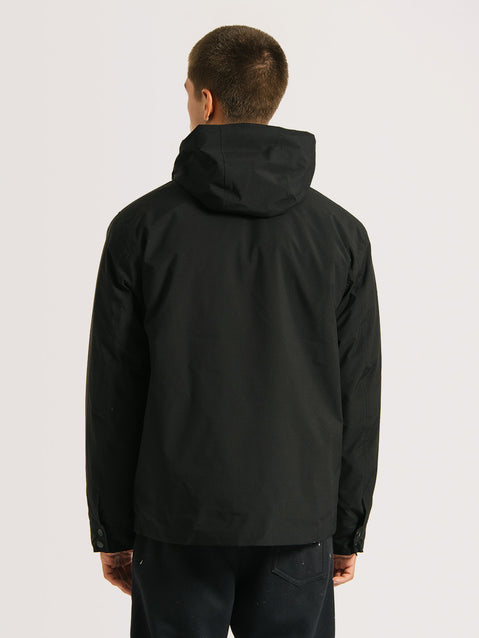 Homem de costas vestindo uma jaqueta pesada preta 3 em 1 com capuz acolchoado fixo e design minimalista, ideal para proteção contra o frio e chuvas.