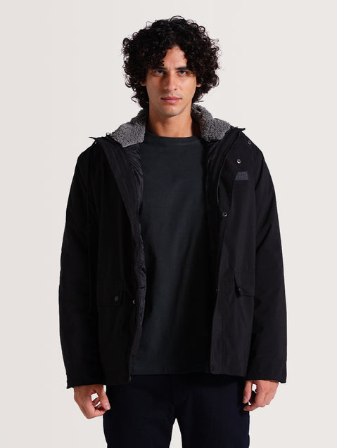 Homem usando jaqueta pesada preta 3 em 1 aberta, exibindo forro interno cinza e acolchoado, com design funcional, ideal para clima frio.