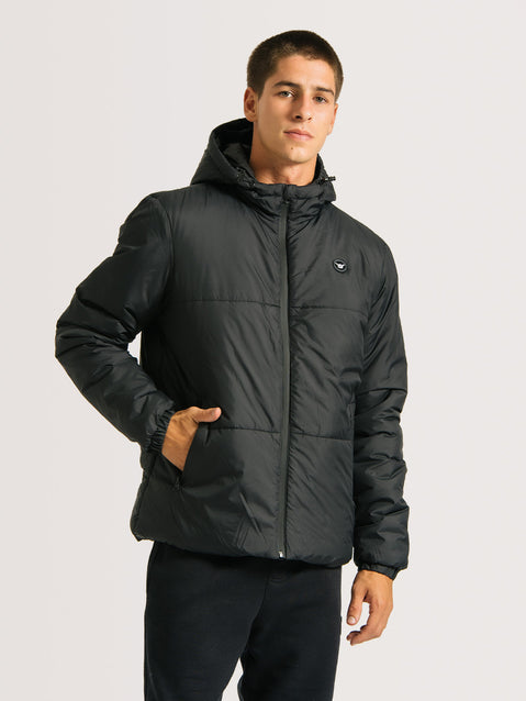 Homem vestindo jaqueta puffer preta com capuz, zíper frontal e bolsos laterais. A peça tem visual acolchoado e estilo casual.