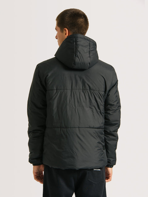Homem vestindo jaqueta puffer preta com capuz acolchoado e acabamento ajustado, vista de costas. A peça tem estilo casual e tecido fosco.