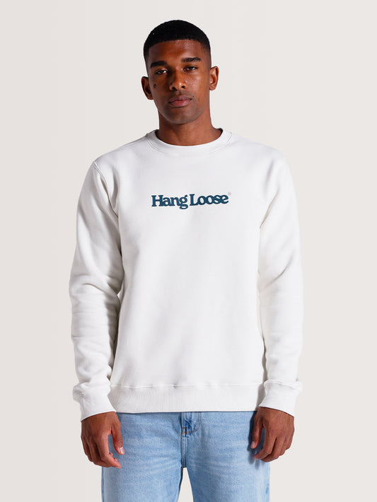 Homem vestindo moletom careca off white felpado com gola redonda, estampa "Hang Loose" azul no peito e modelagem casual. Combina com calça jeans azul clara.