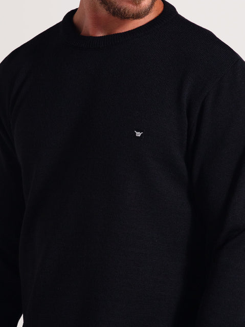 Homem usando tricot preto de manga longa com gola redonda e detalhe minimalista no peito, sobre fundo claro.