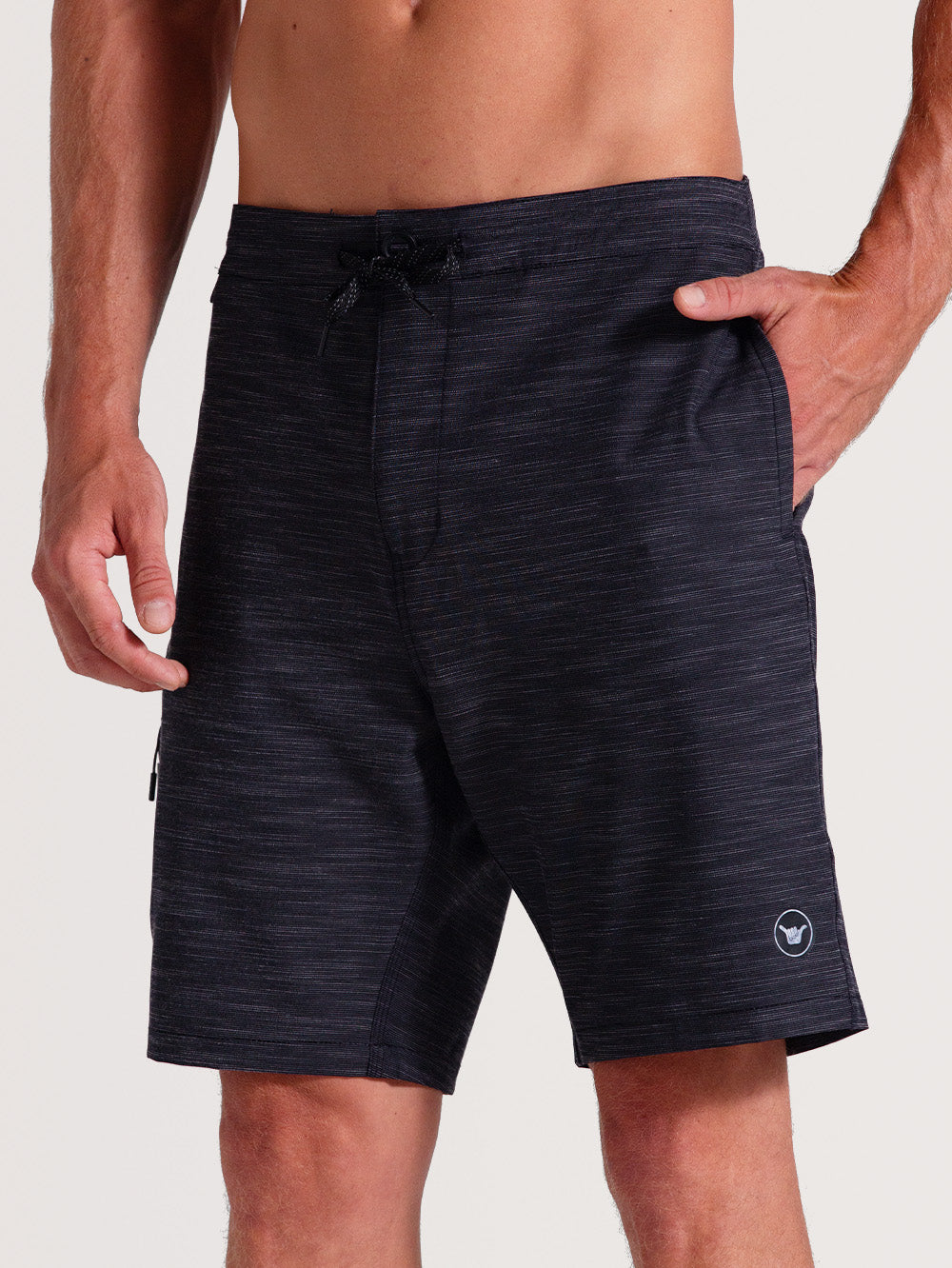 Bermuda híbrida 19 polegadas preto com tecido mesclado, ajuste por cordão na cintura, bolso lateral com zíper e pequeno logo branco próximo à barra.
