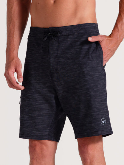 Bermuda híbrida 19 polegadas preto com tecido mesclado, ajuste por cordão na cintura, bolso lateral com zíper e pequeno logo branco próximo à barra.