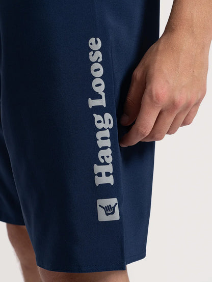 Lateral do boardshort Heather. Nome da marca e símbolo shaka em cinza.