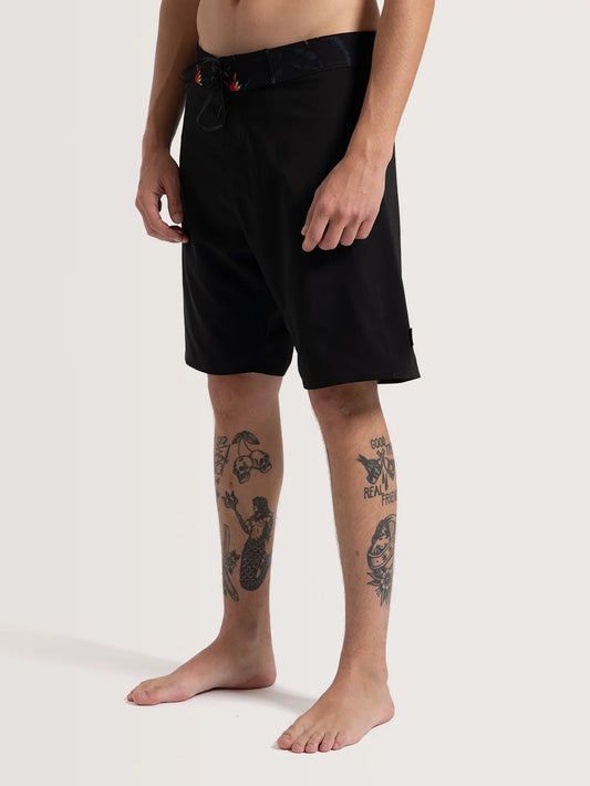 Modelo vestindo boardshort preto da Hang Loose. A peça possui cordão para ajuste e cós com detalhes florais.