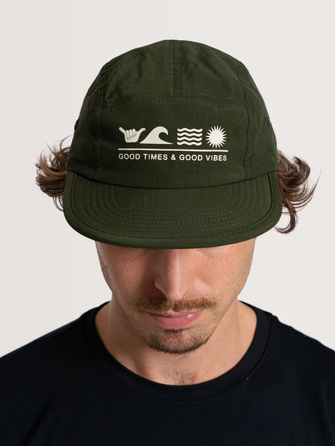 Modelo usando o boné aba reta Hang Loose flat verde com mensagem "Good Times & Good Vibes". Símbolo de onda, sol e mão fazendo o shaka.