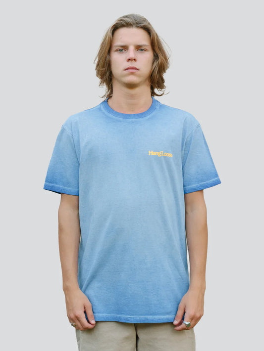 Modelo vestindo camiseta azul caro com escrita "Hang Loose" no peito.