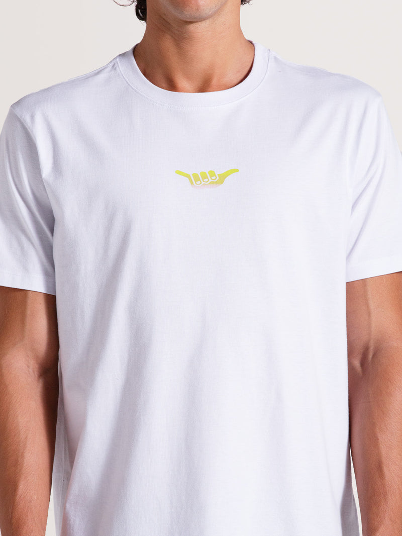 Homem vestindo a camiseta básica branca manga curta com estampa amarela minimalista no peito representando o gesto "Hang Loose".