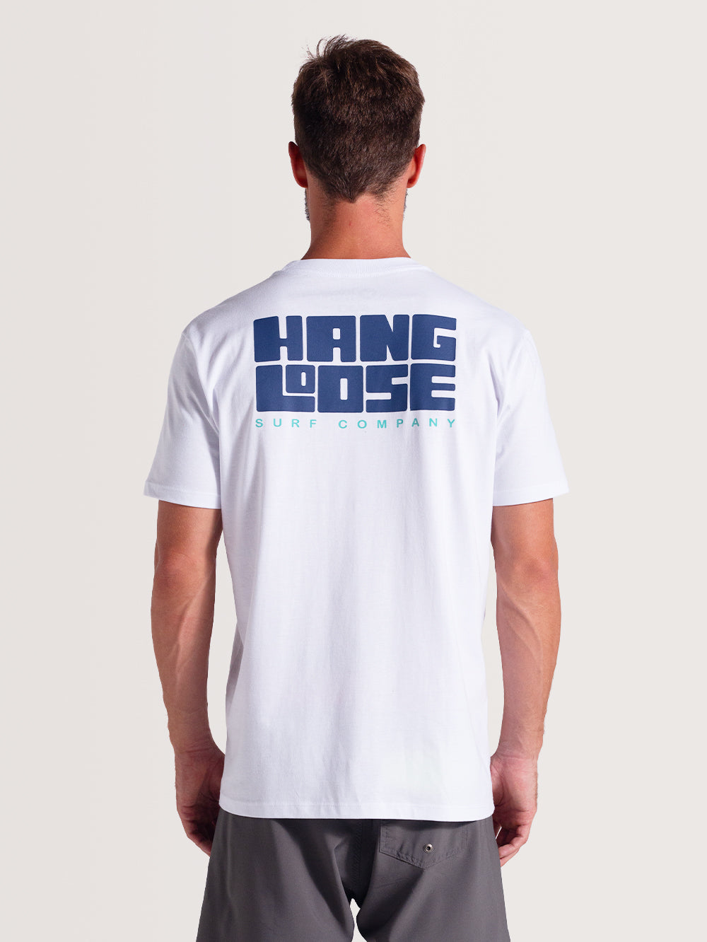 Camiseta branca manga curta com estampa grande em azul "Hang Loose Surf Company" nas costas. Visual casual e descontraído.