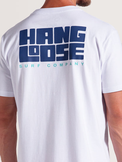 Homem vestindo camiseta branca manga curta com estampa traseira grande em azul escuro "Hang Loose" e texto menor "Surf Company" em azul claro.