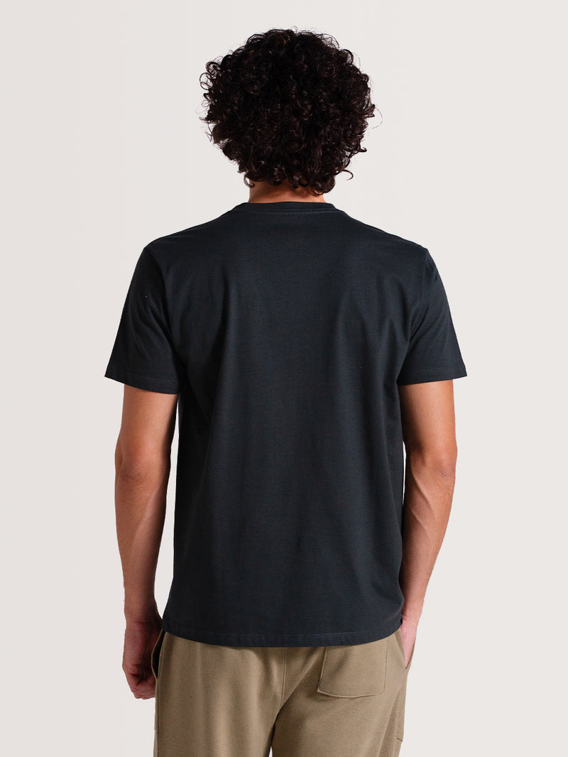 Homem de costas vestindo camiseta cinza algodão manga curta com ajuste reto, combinada com calça caqui.