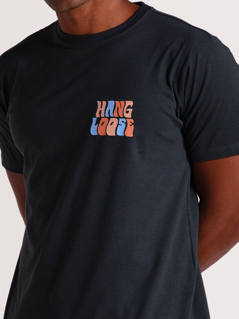 Camiseta cinza básica manga curta com estampa pequena e estilizada "Hang Loose" em laranja e azul no lado esquerdo do peito.