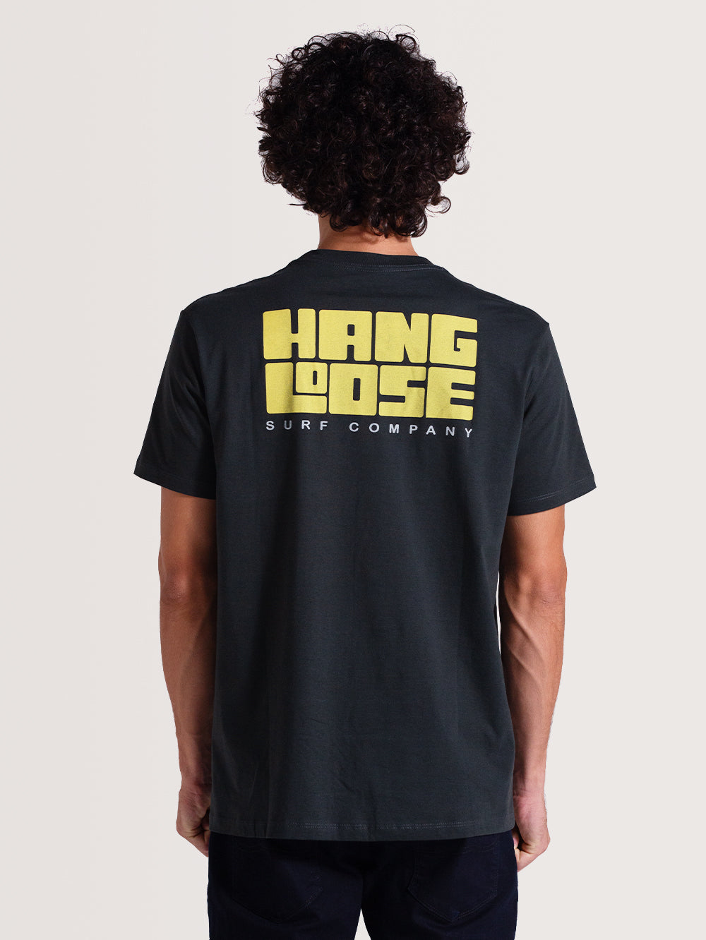 Camiseta cinza manga curta com estampa grande em amarelo "Hang Loose Surf Company" nas costas. Visual casual e descontraído.