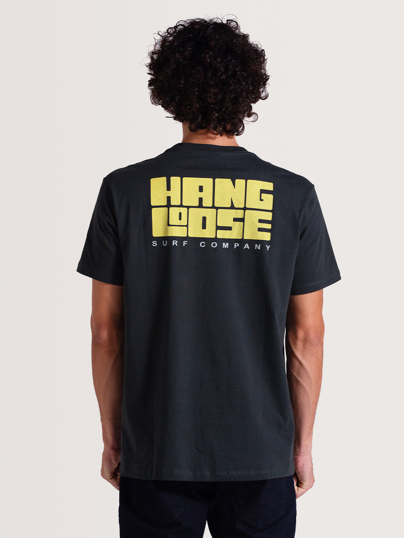 Camiseta cinza manga curta com estampa grande em amarelo "Hang Loose Surf Company" nas costas. Visual casual e descontraído.