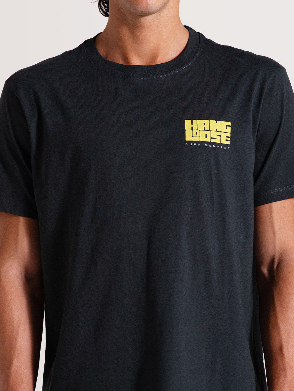 Camiseta cinza manga curta] com logo amarelo "Hang Loose Surf Company" no lado esquerdo do peito. Estilo simples e casual.