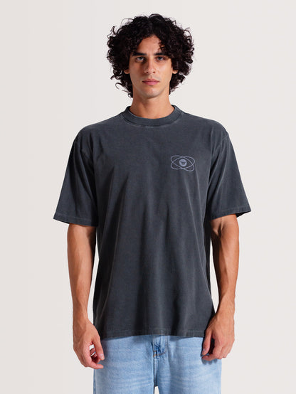 Homem usando camiseta cinza manga longa com design minimalista no peito e tecido em tom desbotado, combinada com jeans claro, em fundo neutro.