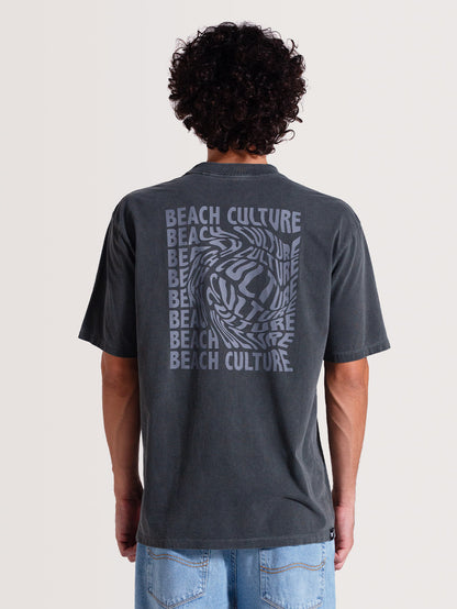 Homem de costas vestindo camiseta cinza manga longa com estampa nas costas escrita "BEACH CULTURE" repetida em azul, formando um efeito ondulado, em fundo claro.