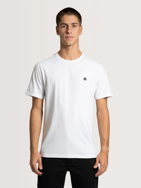 Modelo vestindo a camiseta especial Hang Loose classic na cor branca com pequeno símbolo shaka no peito.
