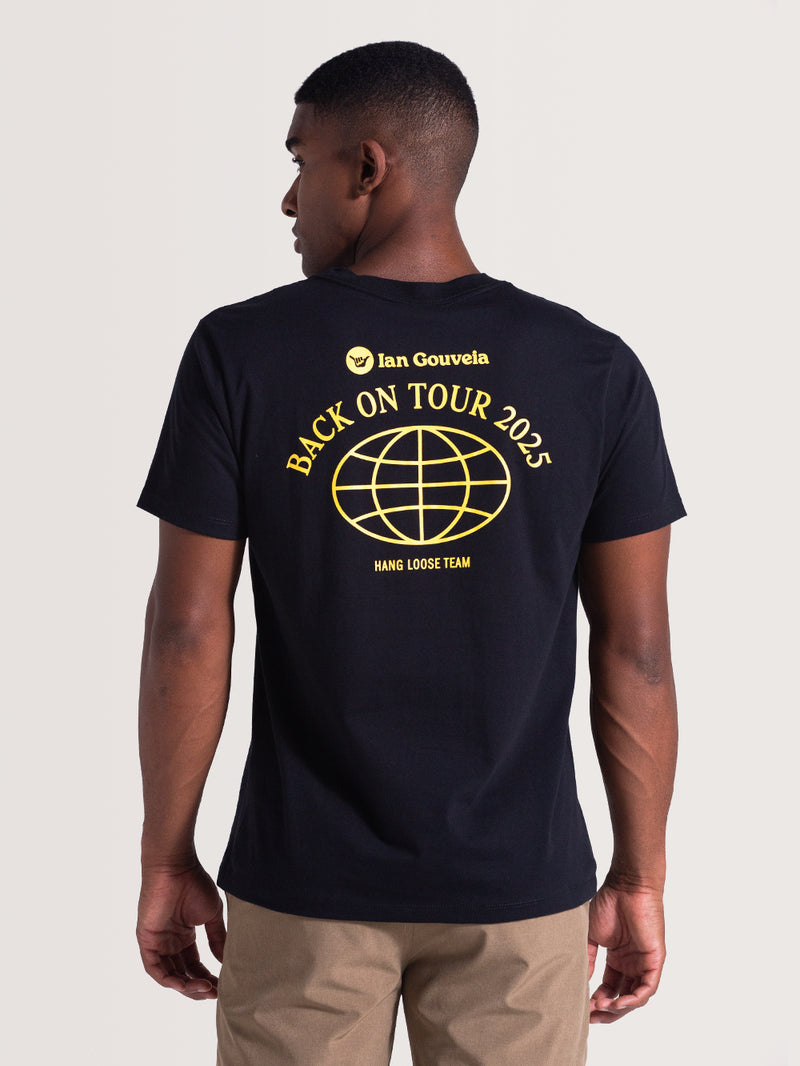 Homem de costas vestindo uma camiseta preta de manga curta da Ian Gouveia com estampa amarela “Back On Tour 2025”, uma esfera e “Hang Loose Team”. Casual e moderna.
