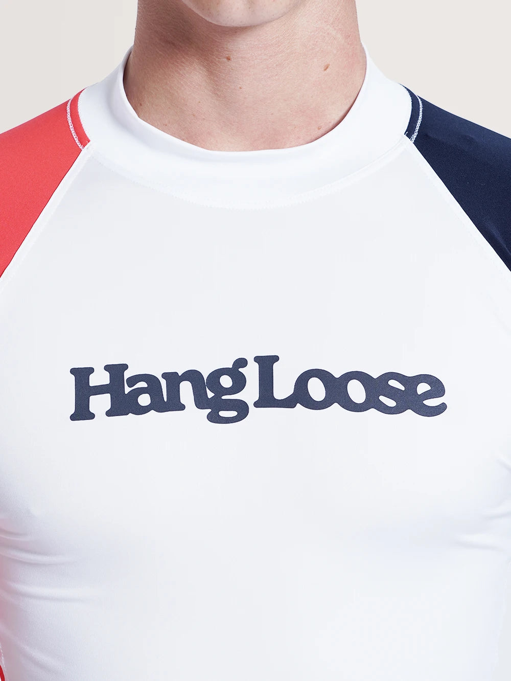 Imagem detalhada da escrita "Hang Loose", em azul, na parte frontal da camiseta surf manga longa branca.