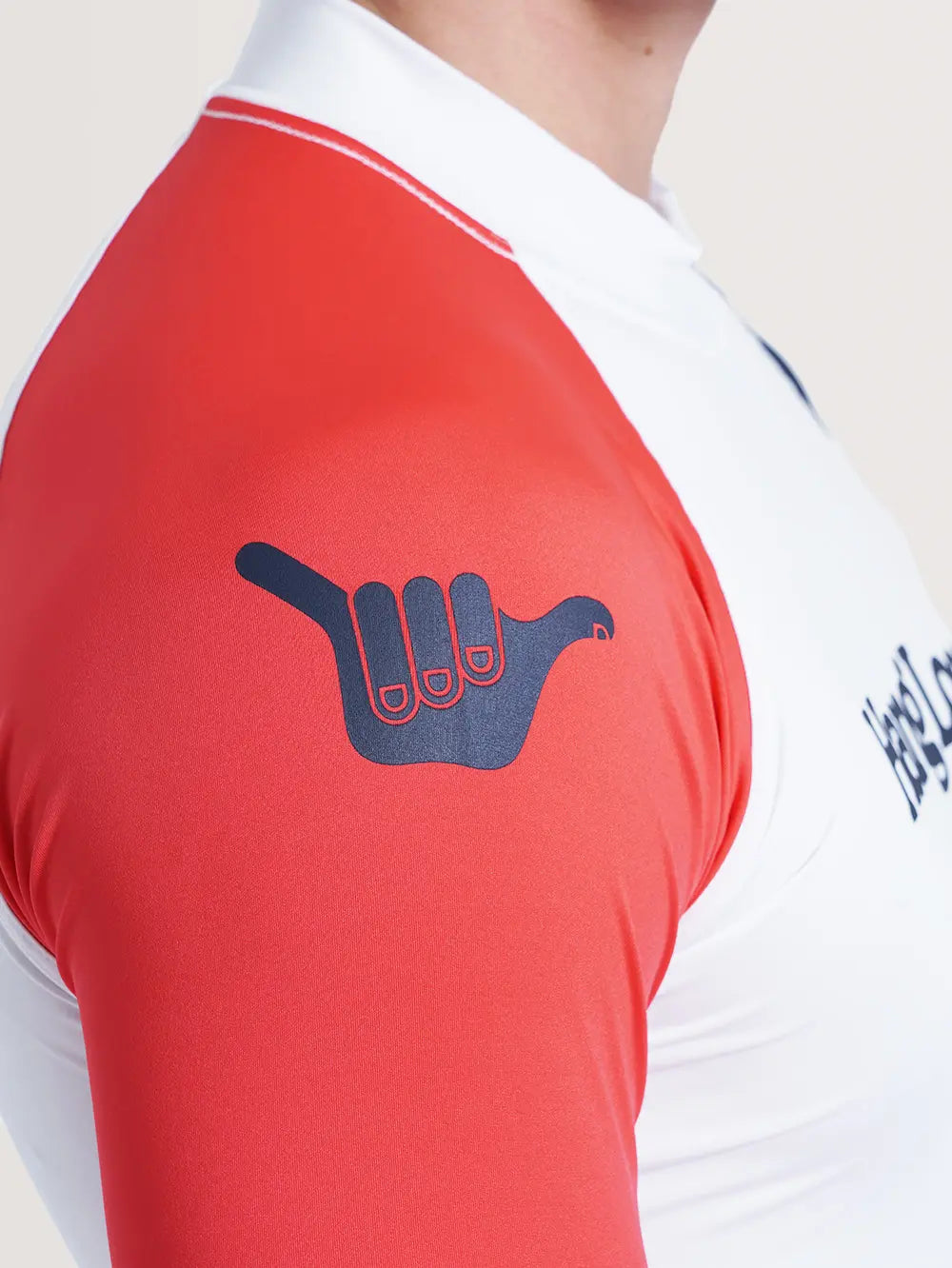 Imagem do ombro direito da camiseta surf manga longa branca, que possui cor vermelha e símbolo Hang Loose em azul.
