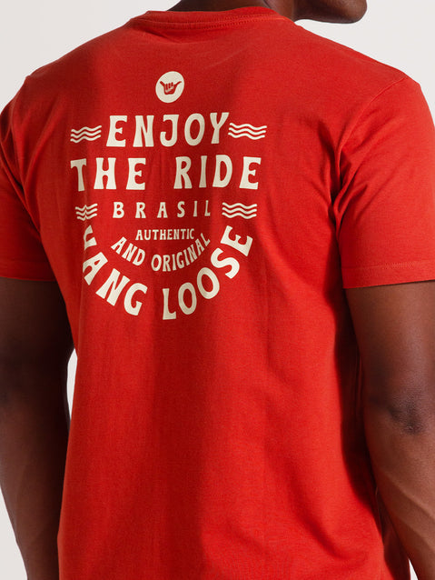 Homem de costas vestindo camiseta vermelha manga curta com estampa branca contendo a frase "Enjoy The Ride Brasil - Authentic and Original Hang Loose".