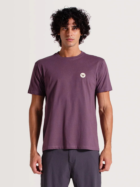 Modelo vestindo a camiseta violeta manga curta Hang Loose. O item conta com design liso e símbolo shaka no peito esquerdo.