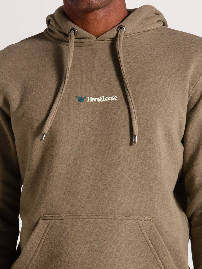 Close do moletom canguru caqui felpado com capuz e bolso frontal. Detalhe de logotipo branco "Hang Loose" no peito e cordões ajustáveis.