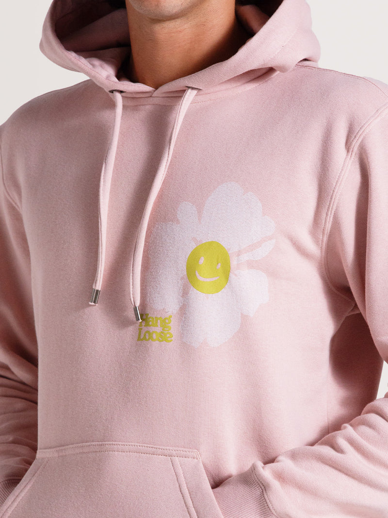 Moletom canguru rosa venice com capuz ajustável, bolso frontal, estampa de flor branca com smile amarelo e logo "Hang Loose" no peito. Estilo casual e descontraído.