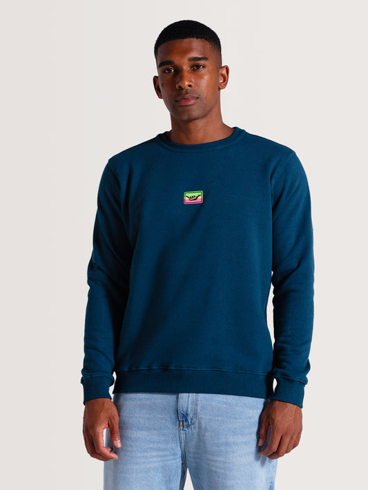Moletom careca azul em tom azul escuro, com logo minimalista colorido no peito. Corte reto, punhos e barra ajustados, perfeito para ocasiões casuais.