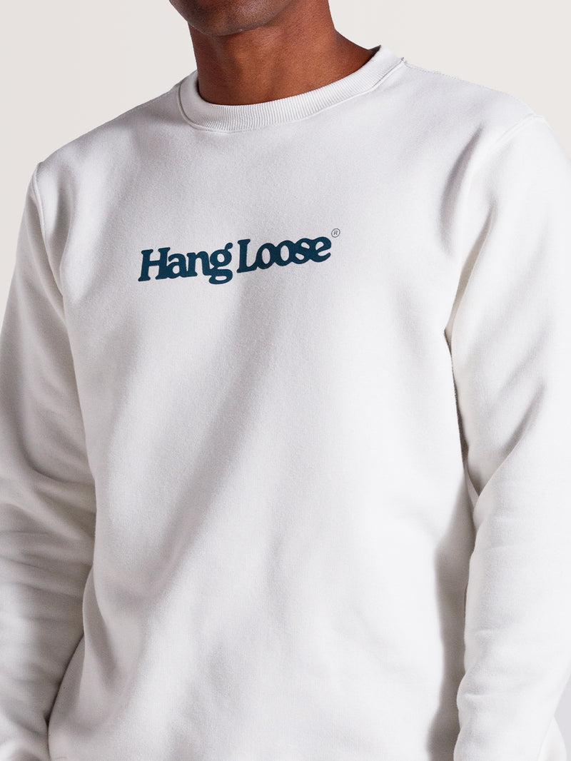 Homem vestindo moletom careca off white felpado com gola redonda e estampa frontal "Hang Loose" em azul escuro. Modelagem casual e tecido confortável.