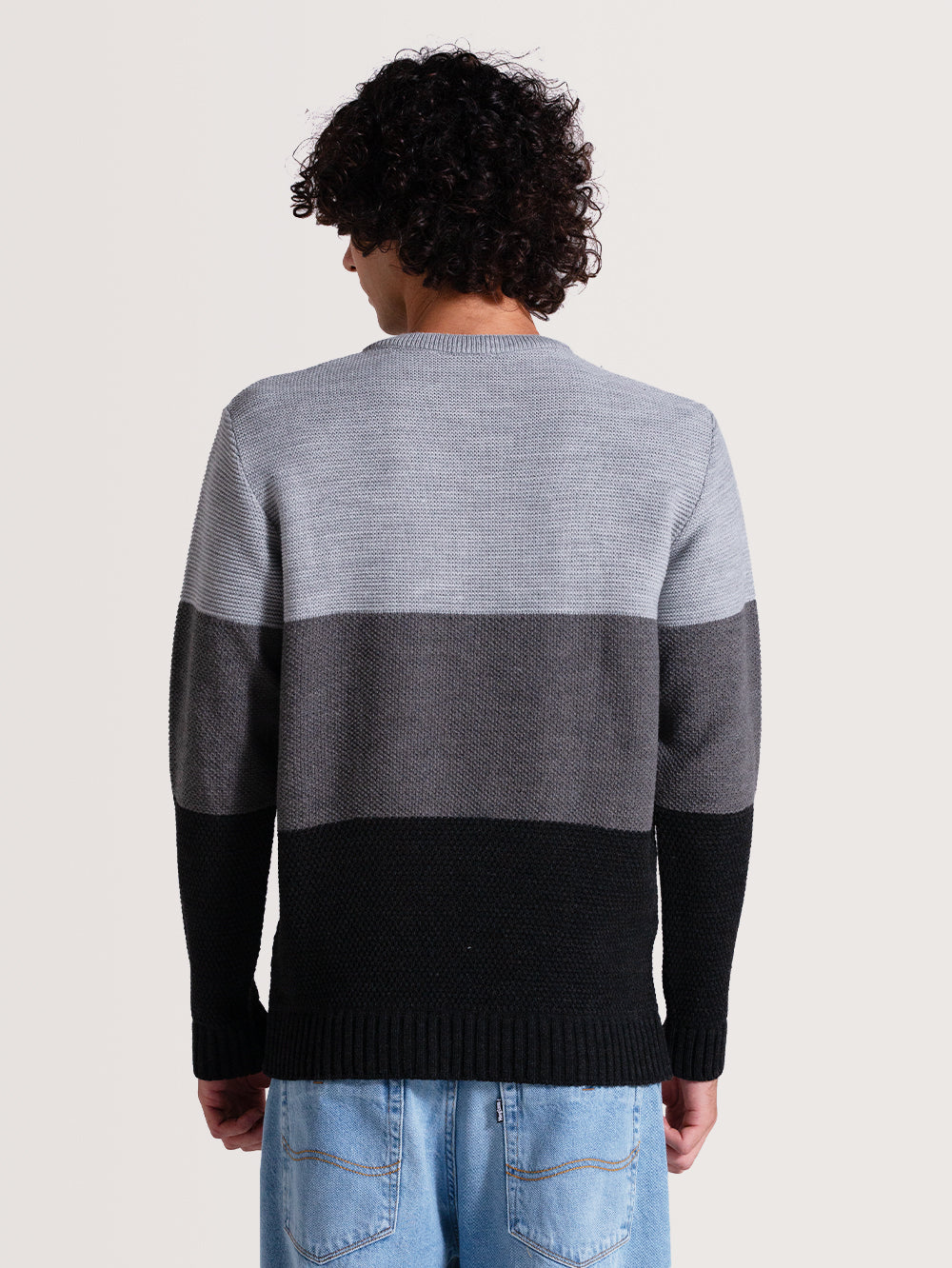 Homem de costas vestindo um tricot cinza com listras horizontais em tons de cinza e preto. Modelo de textura suave e corte reto.