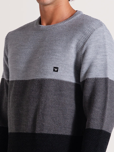 Close de tricot cinza com gola redonda e padrão de listras em tons de cinza e preto. Detalhe de patch discreto no lado esquerdo do peito.